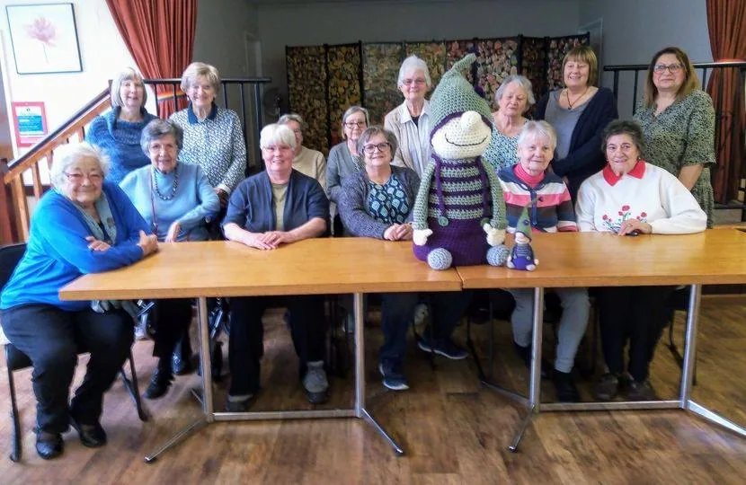 Oswestry Knitters sitting at a table with a big, knitted Smudge